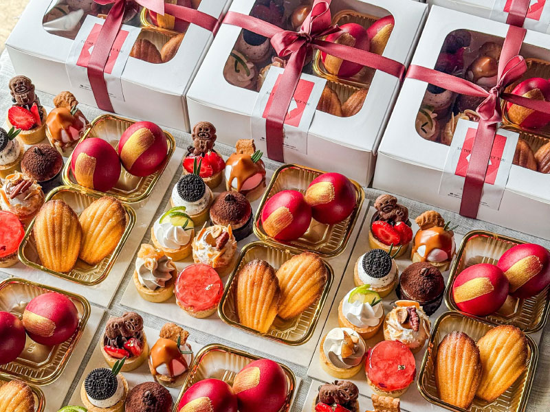 Dessert gift boxes with red ribbons, madeleines, fruit tarts and celebration eggs